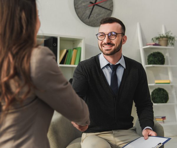 happy psychologist and patient shaking hands in doctors office